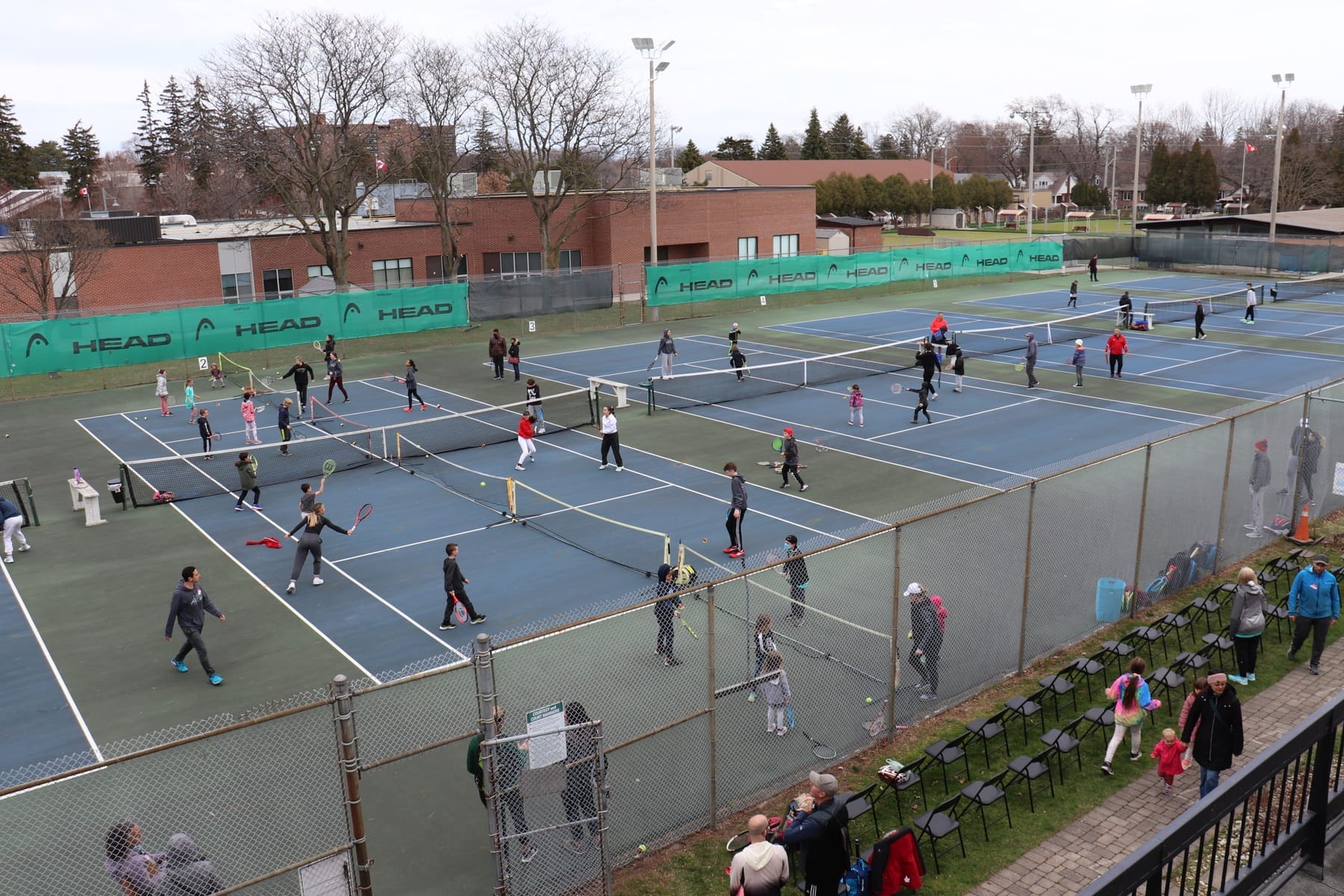 Aerial view of Burlington Tennis Club's outdoor courts filled with children playing during a Tennis Rocks event.
