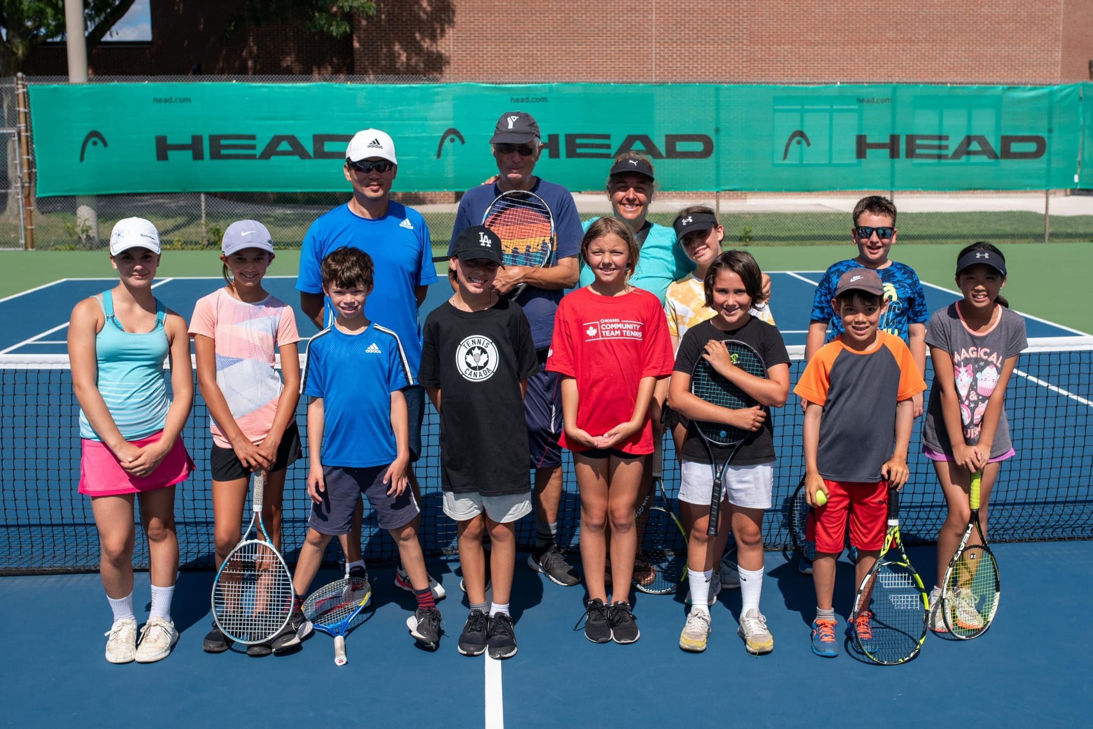 Burlington Tennis Club juniors gathered with Bruce Cates and coaches at the net.
